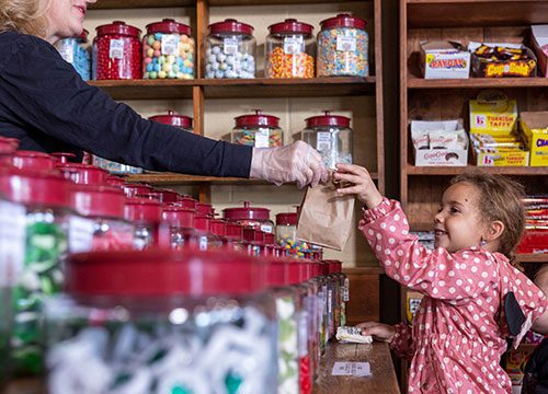 A woman handing candy to a girl in a wheelchair.